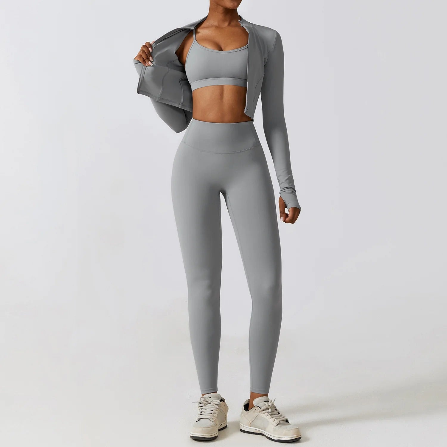 Model wearing Tempo 3-piece women’s training set in mist grey, sports bra, leggings and zip top